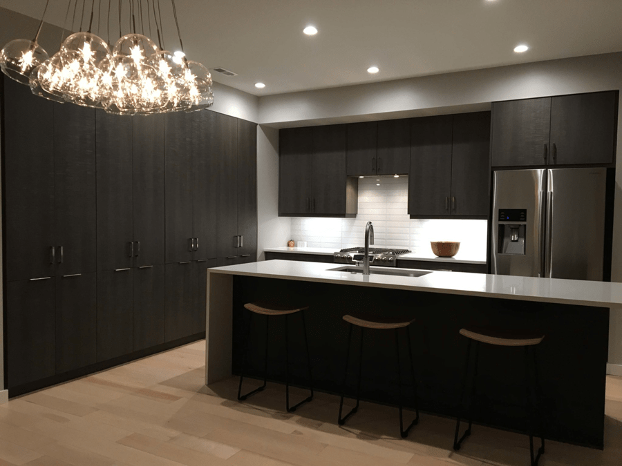 A very simple yet sleek kitchen design featuring black cabinetry, steel accents in the appliances, and floor to ceiling storage space.